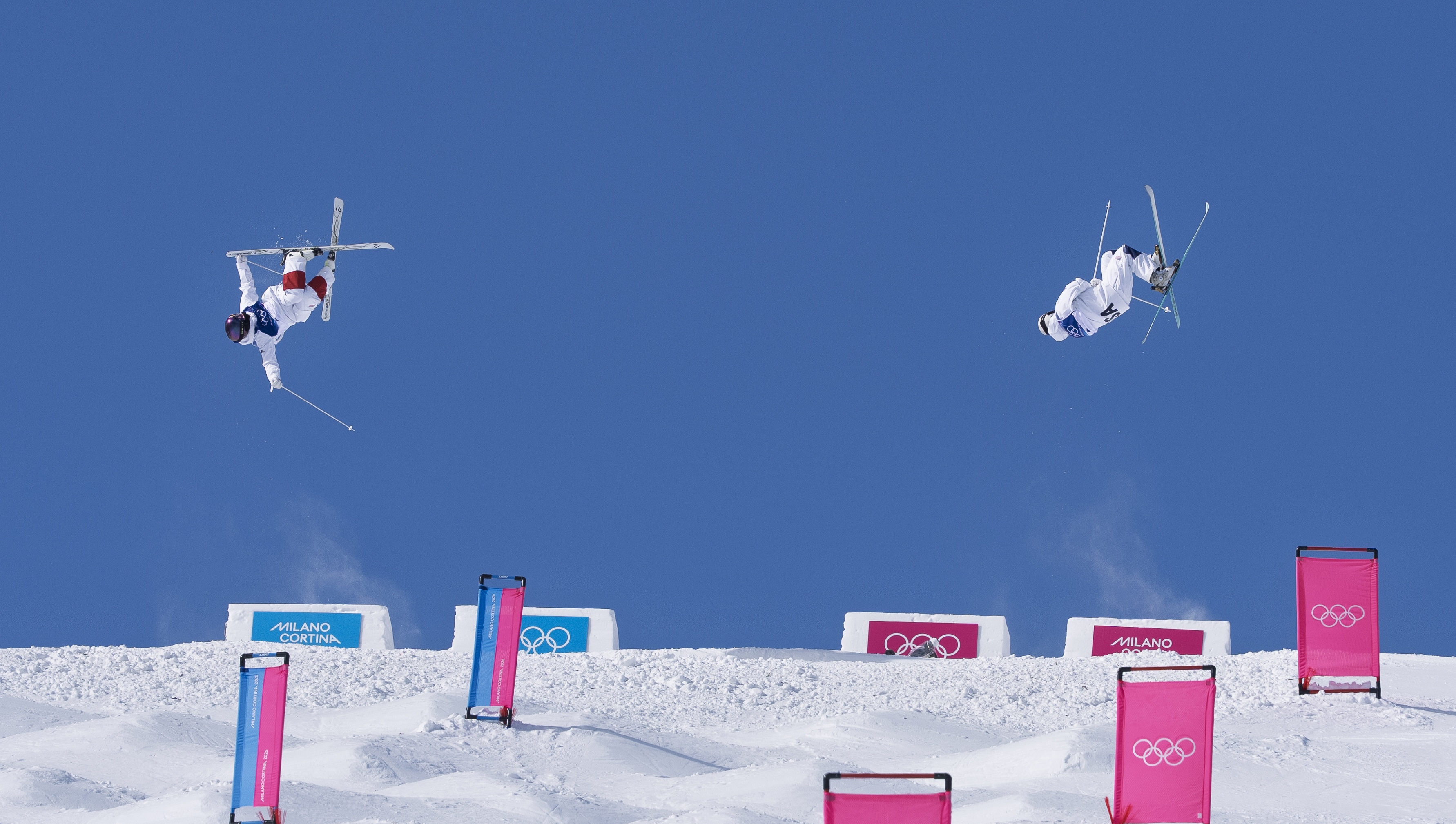 Landon Wendler completes his top air trick in dual moguls side by side with another athlete at the 2026 Winter Olympics
