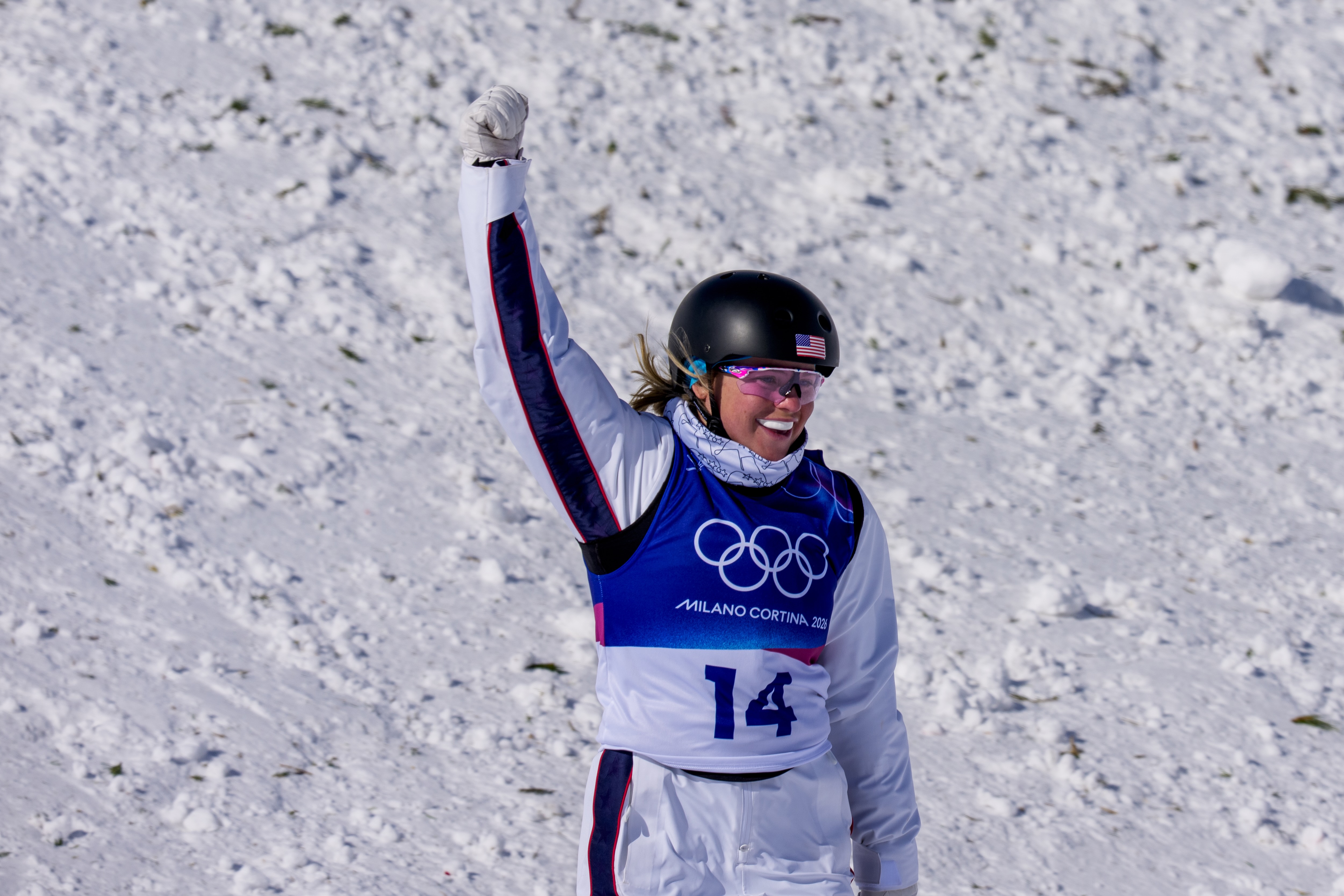 Kyra Dossa celebrates with her hand up after landing a jump at the 2026 Olympic Winter Games