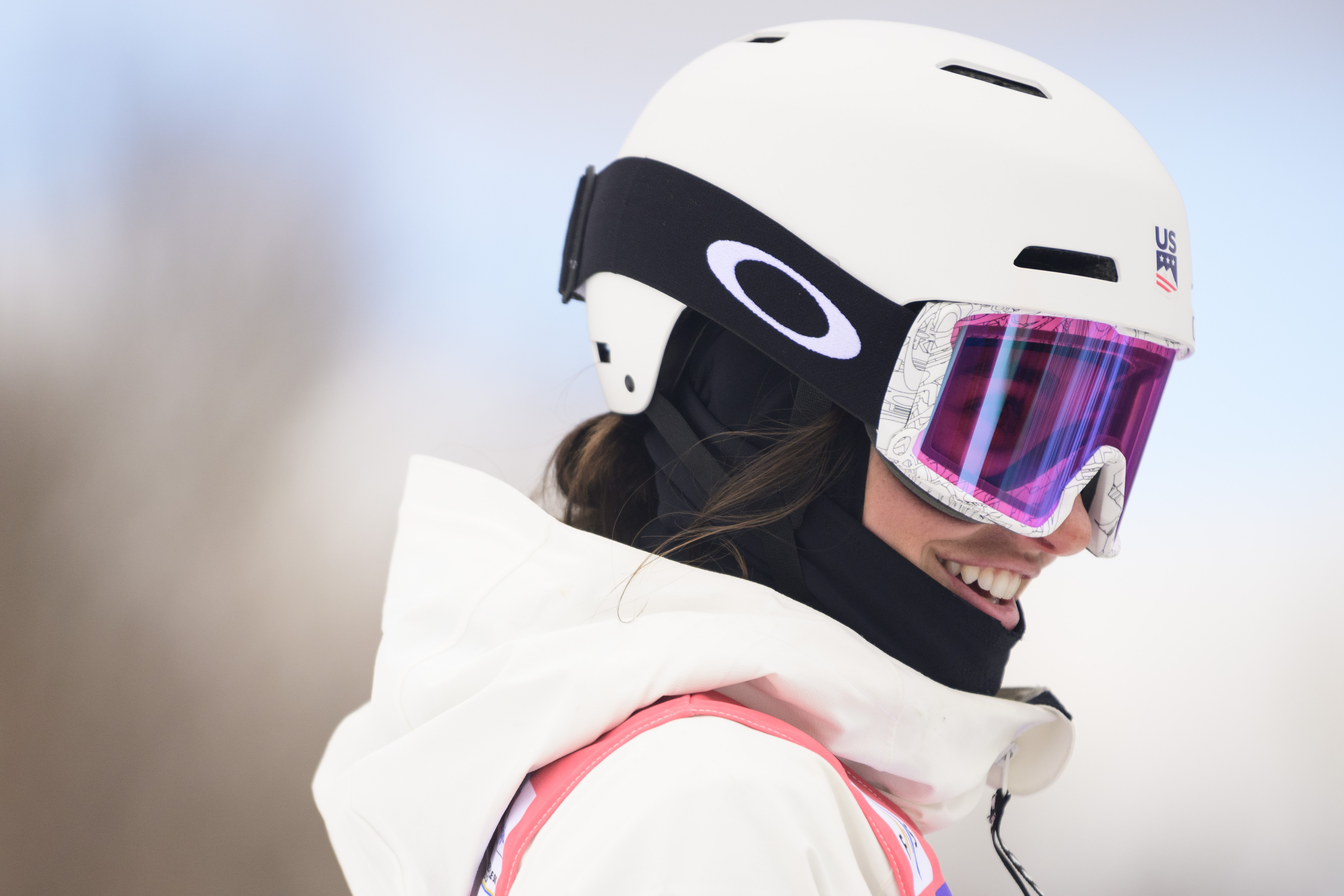 Abby McLarnon smiles at the top of a moguls course in the sun.