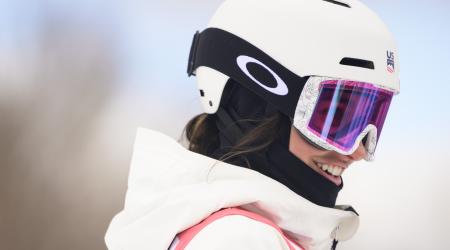 Abby McLarnon smiles at the top of a moguls course in the sun.